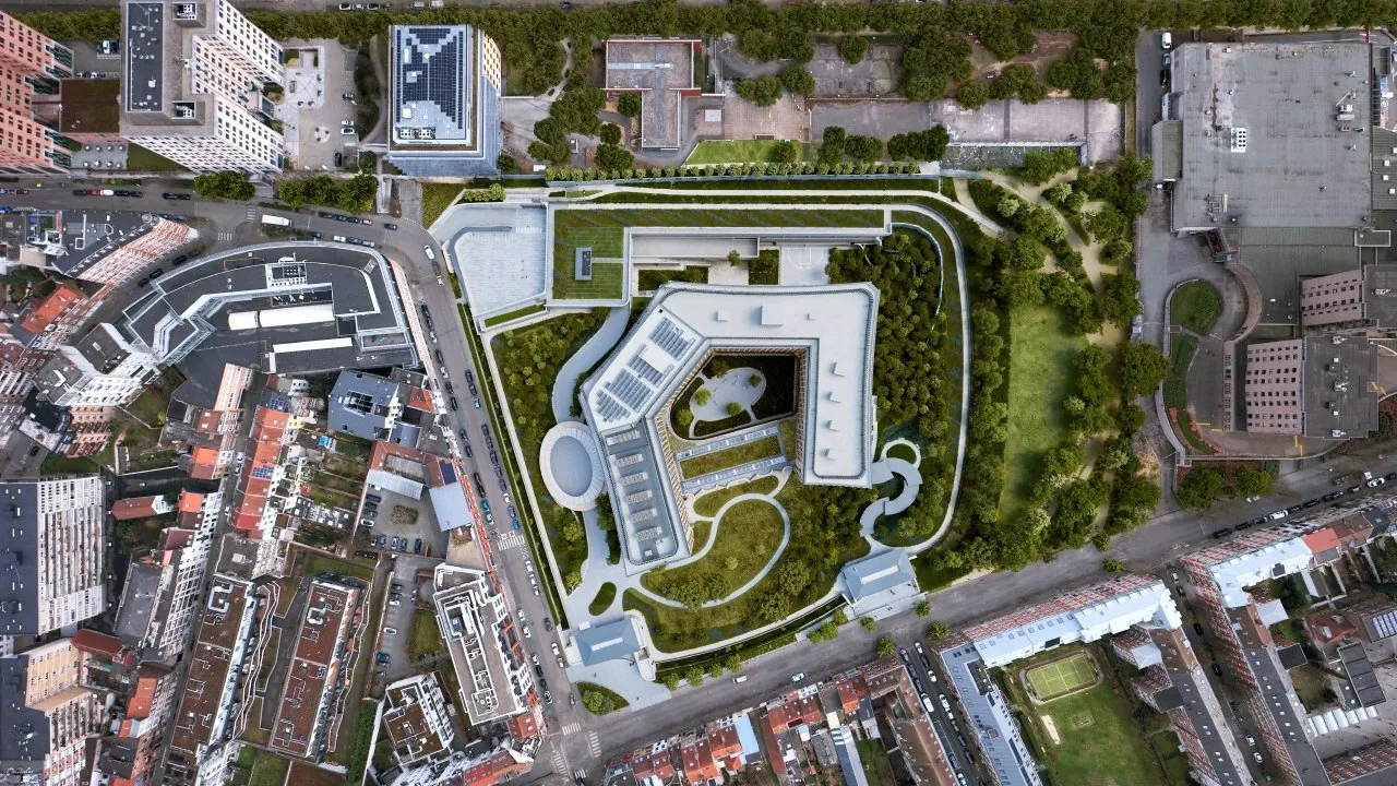 Photo aérienne montrant un bâtiment moderne avec des espaces verts autour dans une zone urbaine dense.
